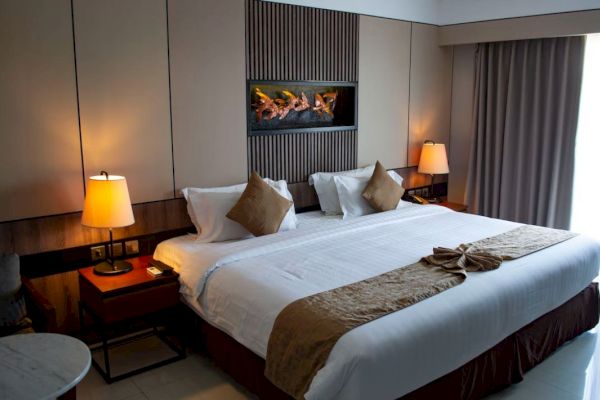 A well-decorated hotel room with a large bed, bedside tables, lamps, and a decorative headboard, creating a cozy atmosphere.