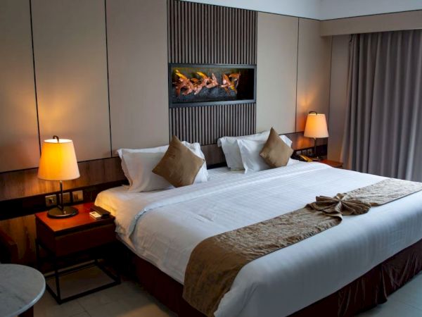 A well-decorated hotel room with a large bed, bedside tables, lamps, and a decorative headboard, creating a cozy atmosphere.