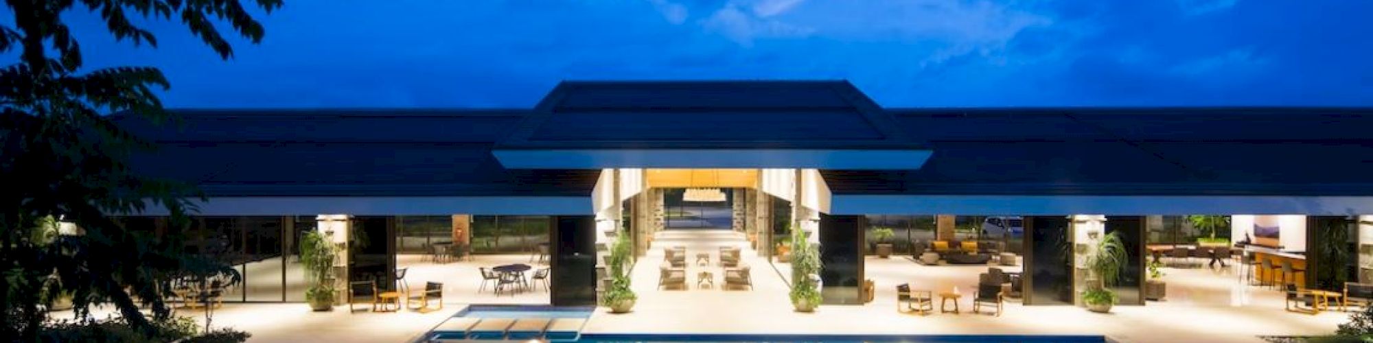 A luxurious, illuminated building with an outdoor pool against a twilight sky creates an inviting and serene scene.