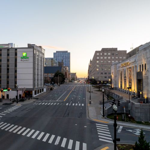 A city street scene at dawn or dusk, with buildings on both sides, quiet roads, and pedestrian crossings, creating a calm urban atmosphere.