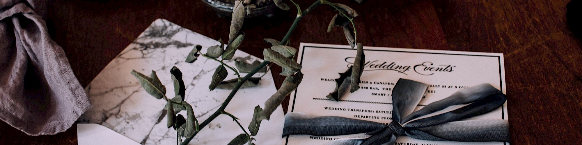 A table with plates, bowls, a branch, and an envelope with a card tied by a ribbon.